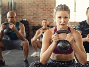 A gym instructor holding a kettle bell with her clients